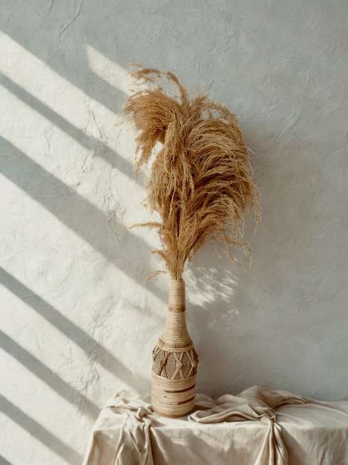 A bottle shaped flower vase wrapped in the finest selection of the raffia plats, with slight contrast in tones which ties it together. It is filled with pampas grass which is designed to last but as a filler