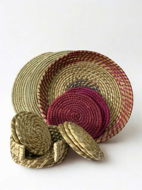 Beige placemats, purple trivets, and wave tray styled with woven coasters on dining table. Handcrafted table set in beige and purple tones with natural fiber texture. The Essence Set by Aduné featuring artisanal placemats, trivets, and coasters. Minimalist home decor set in warm neutral and purple hues.